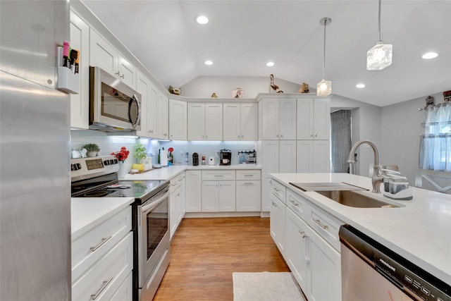 5 Fox Rd, Middle Island, NY 11953 - kitchen with stainless steel appliances, vaulted ceiling, light countertops, white cabinetry, and recessed lighting