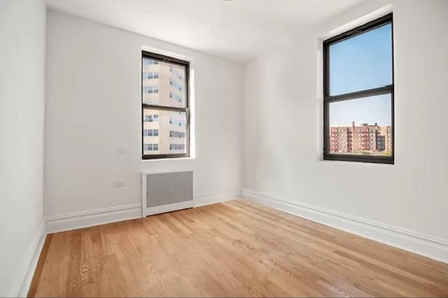 97-25 64th Ave Unit 5D, Rego Park, NY 11374 - empty room featuring radiator, healthy amount of natural light, and light wood-style flooring