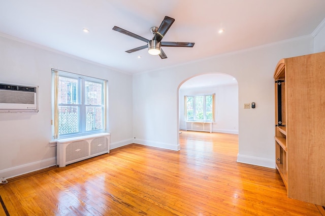 6419 Fitchett St, Rego Park, NY 11374 - empty room featuring radiator heating unit, arched walkways, a wall unit AC, ornamental molding, and light wood-type flooring