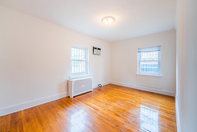 6419 Fitchett St, Rego Park, NY 11374 - empty room featuring radiator, plenty of natural light, light wood-style flooring, and an AC wall unit