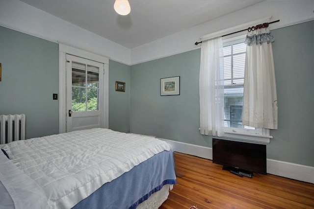 111 S Hamilton St, Poughkeepsie, NY 12601 - bedroom featuring radiator heating unit, multiple windows, and wood finished floors
