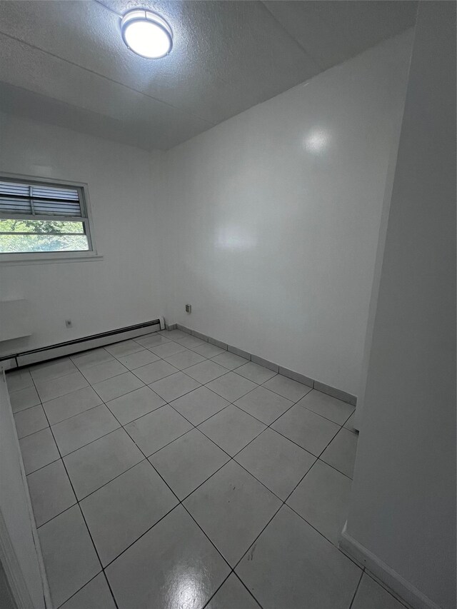 889 E 169th St, Bronx, NY 10459 - spare room with baseboard heating, light tile patterned floors, and a textured ceiling