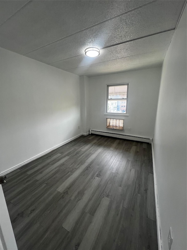 889 E 169th St, Bronx, NY 10459 - empty room with baseboard heating, dark wood finished floors, and a textured ceiling