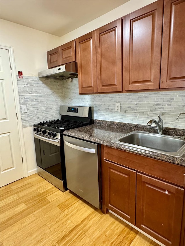 324 Concord Ln, Middletown, NY 10940 - kitchen featuring appliances with stainless steel finishes, under cabinet range hood, light wood-style flooring, dark countertops, and tasteful backsplash
