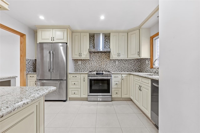 205-06 26th Ave, Bayside, NY 11360 - kitchen with appliances with stainless steel finishes, cream cabinetry, wall chimney exhaust hood, light tile patterned floors, and recessed lighting