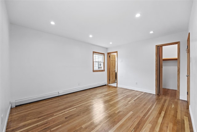 205-06 26th Ave, Bayside, NY 11360 - unfurnished bedroom featuring baseboard heating, light wood finished floors, a walk in closet, and recessed lighting