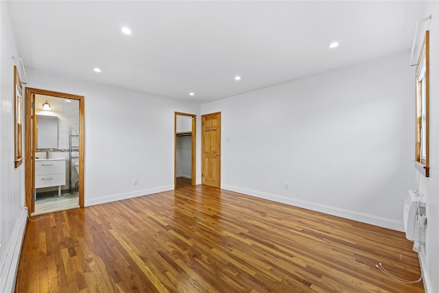 205-06 26th Ave, Bayside, NY 11360 - unfurnished bedroom with wood finished floors, recessed lighting, a spacious closet, and ensuite bathroom