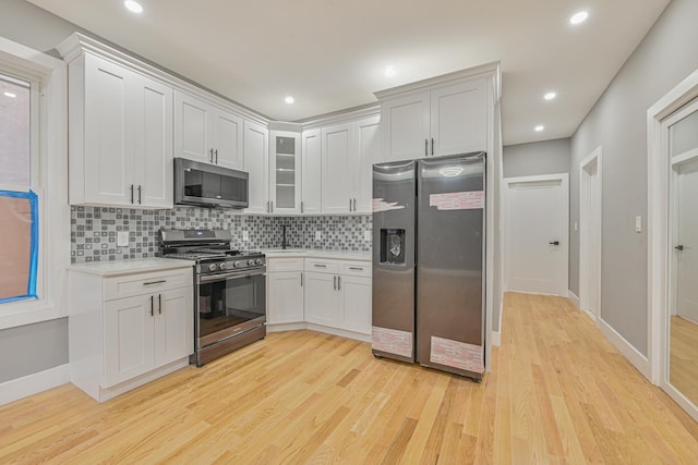 610 Sheffield Ave, Brooklyn, NY 11207 - kitchen featuring stainless steel appliances, light countertops, tasteful backsplash, light wood-style floors, and glass insert cabinets