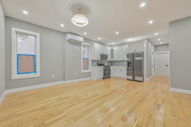 610 Sheffield Ave, Brooklyn, NY 11207 - kitchen with appliances with stainless steel finishes, an AC wall unit, backsplash, light wood-type flooring, and white cabinets