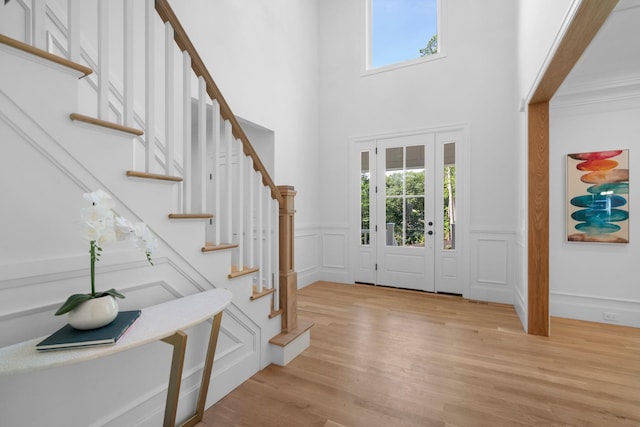 32 Middleville Rd Unit 2, Northport, NY 11768 - foyer entrance featuring stairway, a decorative wall, light wood-type flooring, a wainscoted wall, and a high ceiling