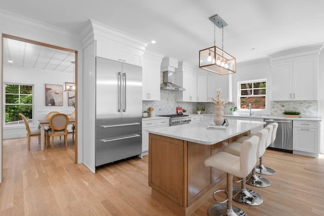 32 Middleville Rd Unit 2, Northport, NY 11768 - kitchen featuring appliances with stainless steel finishes, wall chimney exhaust hood, light wood-style flooring, white cabinets, and backsplash