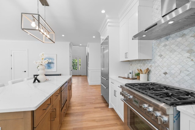 32 Middleville Rd Unit 2, Northport, NY 11768 - kitchen with high end appliances, wall chimney exhaust hood, decorative backsplash, light wood finished floors, and ornamental molding