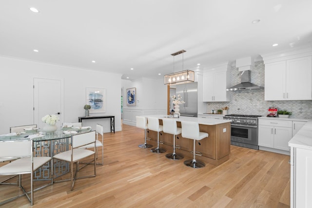 32 Middleville Rd Unit 2, Northport, NY 11768 - kitchen featuring premium appliances, wall chimney exhaust hood, a kitchen island, decorative backsplash, and white cabinetry
