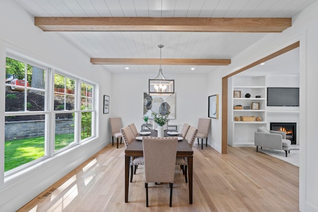 30 Middleville Rd, Northport, NY 11768 - dining room with plenty of natural light, light wood-type flooring, a glass covered fireplace, a chandelier, and beamed ceiling