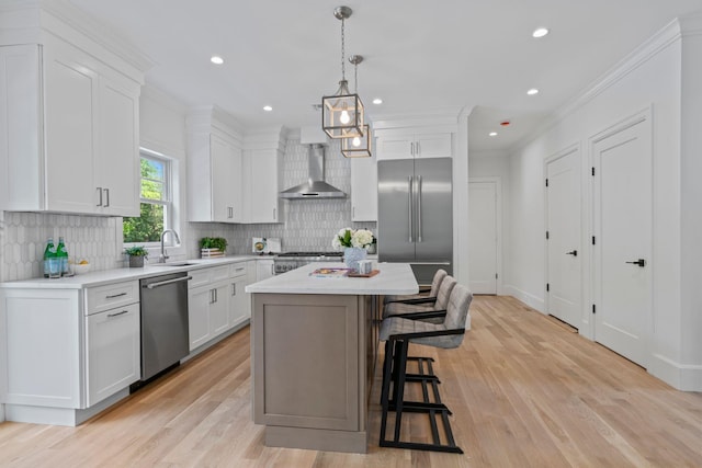 30 Middleville Rd, Northport, NY 11768 - kitchen featuring appliances with stainless steel finishes, wall chimney exhaust hood, a kitchen breakfast bar, light countertops, and backsplash