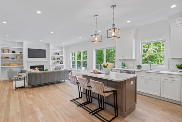 30 Middleville Rd, Northport, NY 11768 - kitchen with white cabinetry, light countertops, a center island, a lit fireplace, and ornamental molding