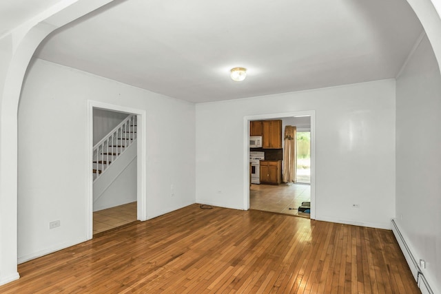 117 Glenwood Rd, Glenwood Landing, NY 11547 - unfurnished room featuring a baseboard heating unit, hardwood / wood-style flooring, arched walkways, and stairway