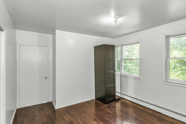 117 Glenwood Rd, Glenwood Landing, NY 11547 - unfurnished bedroom featuring a baseboard radiator, dark wood-style flooring, and multiple windows