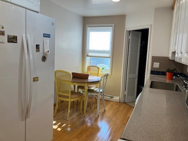 20 Chapel Pl Unit 1H, Great Neck, NY 11021 - kitchen featuring freestanding refrigerator, light wood finished floors, white cabinetry, and backsplash