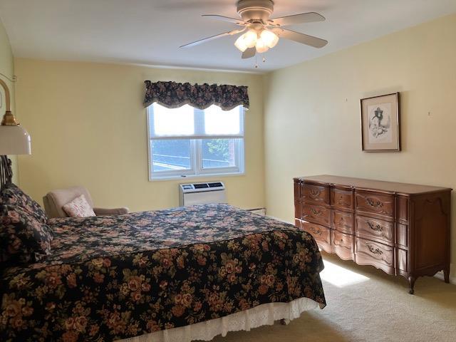 20 Chapel Pl Unit 1H, Great Neck, NY 11021 - carpeted bedroom with a wall mounted air conditioner and a ceiling fan