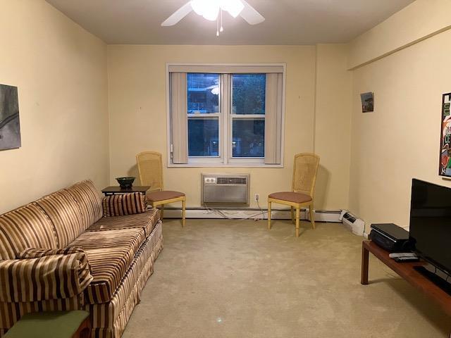 20 Chapel Pl Unit 1H, Great Neck, NY 11021 - living area featuring a wall mounted AC, light colored carpet, and a ceiling fan