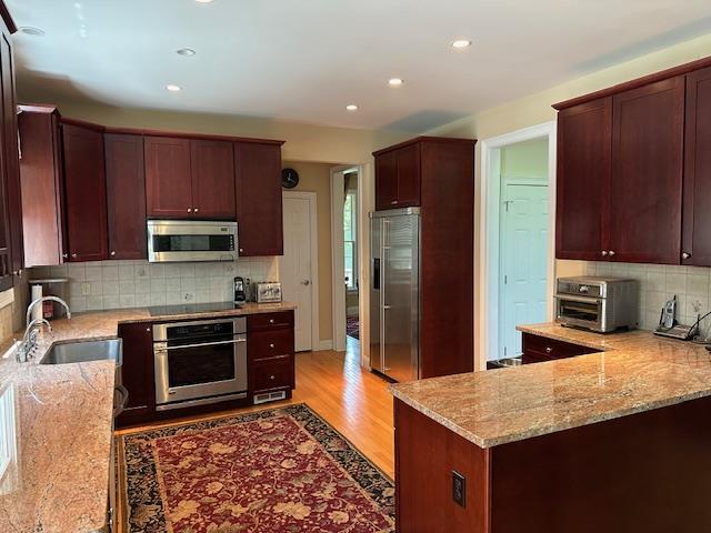 1 Sunset Ave, East Quogue, NY 11942 - kitchen with appliances with stainless steel finishes, light stone counters, tasteful backsplash, recessed lighting, and light wood-style floors