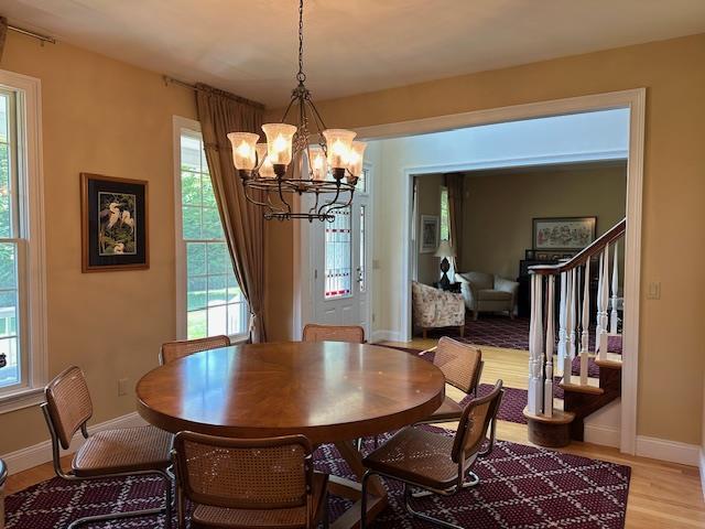 1 Sunset Ave, East Quogue, NY 11942 - dining space featuring a chandelier, stairs, light wood finished floors, and plenty of natural light