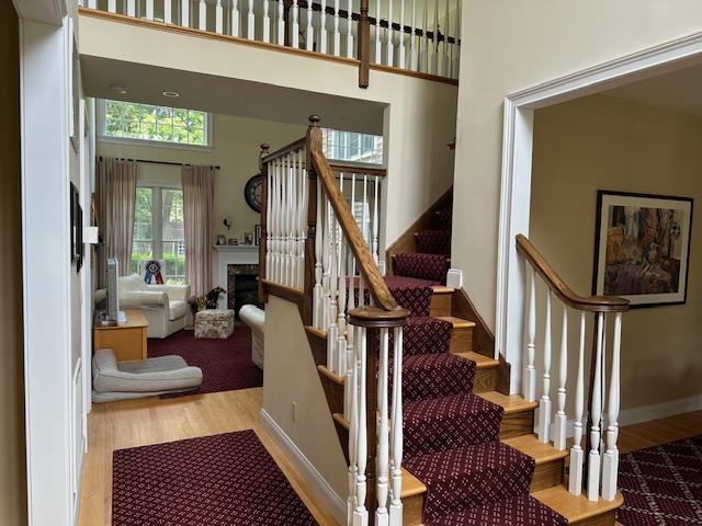 1 Sunset Ave, East Quogue, NY 11942 - stairway featuring wood finished floors, a towering ceiling, and a fireplace