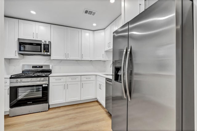 189 Jacob St, Elmont, NY 11003 - kitchen with stainless steel appliances, white cabinetry, light wood finished floors, light countertops, and recessed lighting