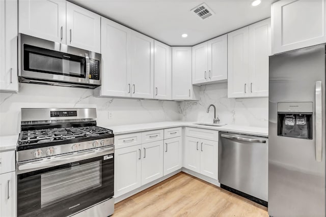 189 Jacob St, Elmont, NY 11003 - kitchen with stainless steel appliances, light countertops, white cabinetry, light wood-type flooring, and recessed lighting