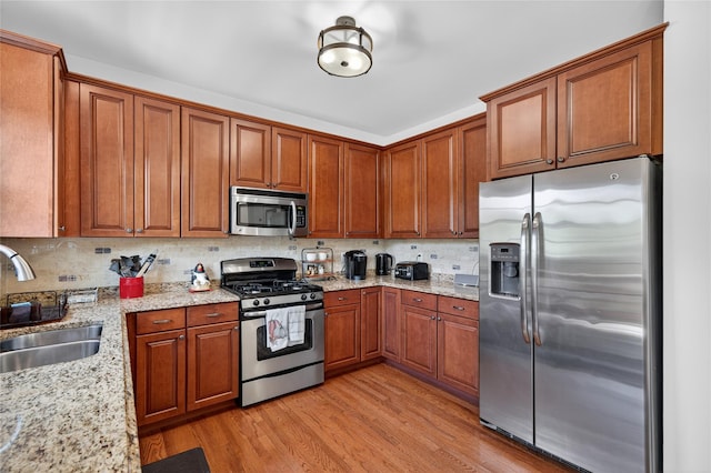 2 Primrose Ln, Chester, NY 10918 - kitchen featuring appliances with stainless steel finishes, light wood finished floors, brown cabinets, light stone counters, and tasteful backsplash