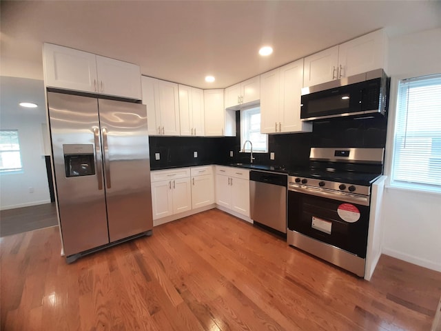 8 Poplar St, Poughkeepsie, NY 12601 - kitchen featuring stainless steel appliances, white cabinets, backsplash, light wood finished floors, and recessed lighting