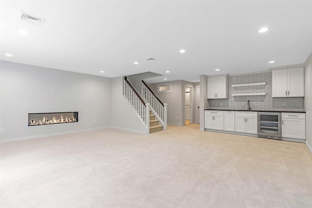 130 Sunset Ln, Greenport, NY 11944 - kitchen featuring beverage cooler, dark countertops, light colored carpet, white cabinets, and recessed lighting