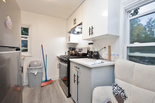 11 E Ave, Middletown, NY 10940 - kitchen with stainless steel gas stove, freestanding refrigerator, under cabinet range hood, light wood finished floors, and light countertops