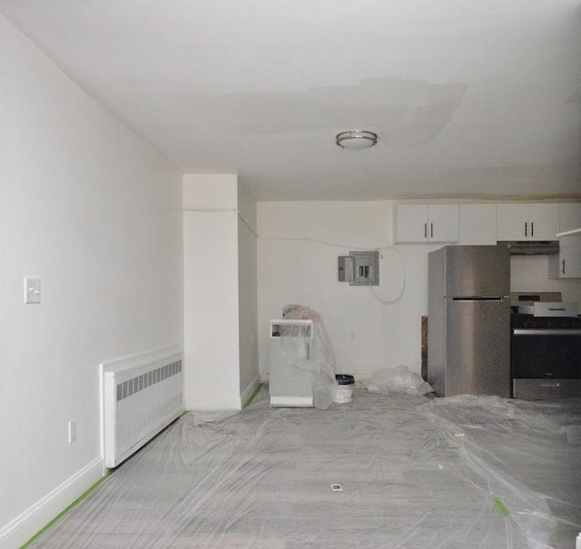 11 E Ave, Middletown, NY 10940 - kitchen featuring range, radiator heating unit, freestanding refrigerator, white cabinetry, and electric panel