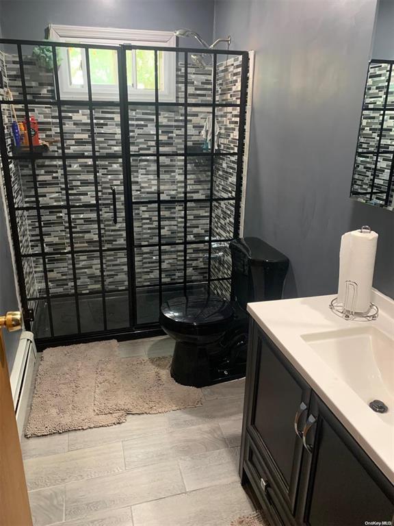 50 Oakland Dr, Riverhead, NY 11901 - full bath with a stall shower, vanity, and baseboard heating