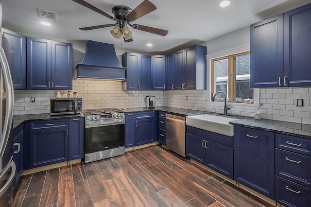6 Youngs Ln, Setauket, NY 11733 - kitchen with appliances with stainless steel finishes, custom range hood, blue cabinetry, ceiling fan, and dark wood finished floors