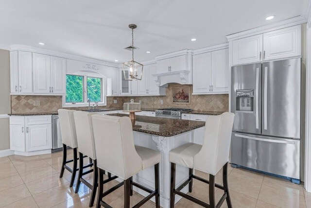 709 Demott Ct, Westbury, NY 11590 - kitchen with stainless steel appliances, white cabinets, a kitchen breakfast bar, hanging light fixtures, and recessed lighting