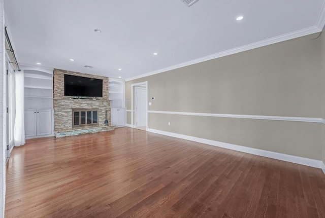 709 Demott Ct, Westbury, NY 11590 - unfurnished living room featuring wood finished floors, ornamental molding, a stone fireplace, built in shelves, and recessed lighting