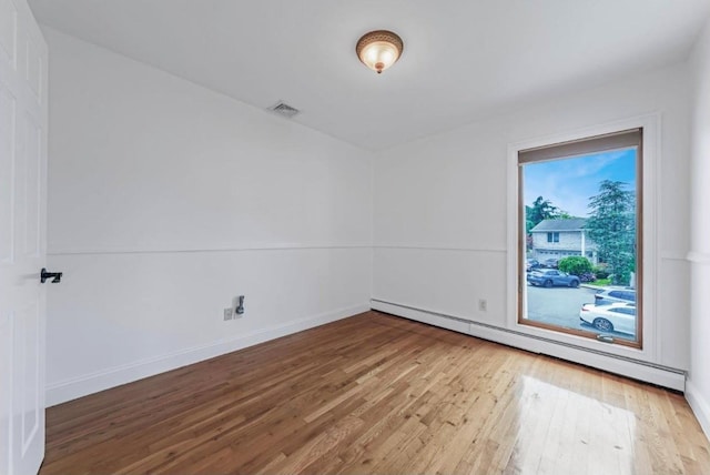709 Demott Ct, Westbury, NY 11590 - spare room featuring a baseboard heating unit and wood finished floors