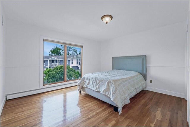709 Demott Ct, Westbury, NY 11590 - bedroom featuring a baseboard radiator and wood finished floors