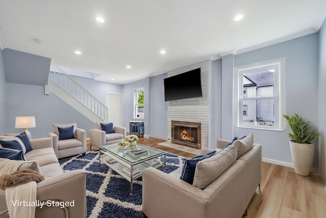 26 Rosedale Ave, Freeport, NY 11520 - living room featuring light wood-style flooring, a brick fireplace, stairs, recessed lighting, and ornamental molding