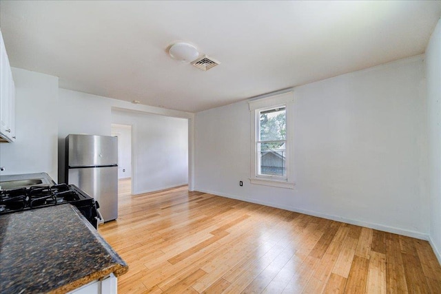 221 E Main St, Middletown, NY 10940 - kitchen with freestanding refrigerator, light wood-type flooring, white cabinets, and range