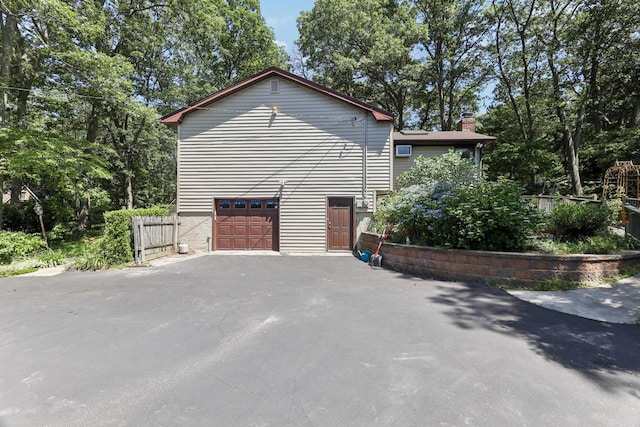 65 Winston Dr, Smithtown, NY 11787 - view of property exterior with asphalt driveway, a chimney, and a garage