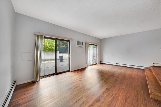 504 Julius Rd Unit 7C, College Point, NY 11356 - spare room with a baseboard heating unit, a wall mounted air conditioner, and wood finished floors