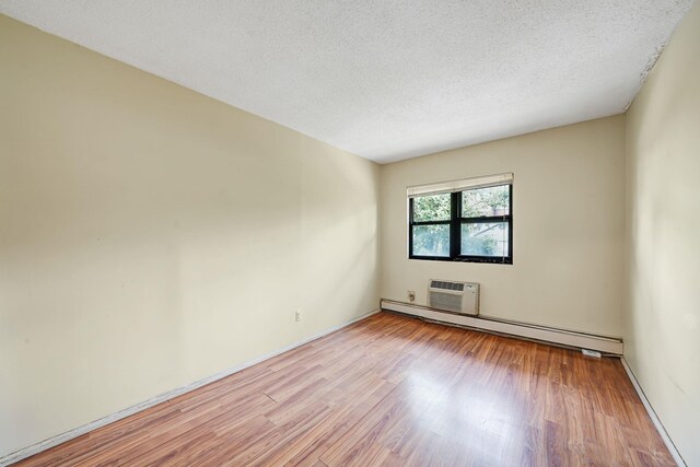 504 Julius Rd Unit 7C, College Point, NY 11356 - unfurnished room featuring a baseboard radiator, wood finished floors, an AC wall unit, and a textured ceiling