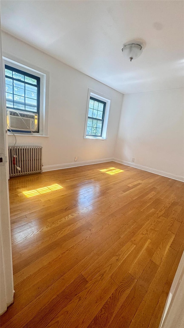 14133 78th Ave Unit 3B, Kew Garden Hills, NY 11367 - spare room with radiator heating unit, cooling unit, and wood finished floors