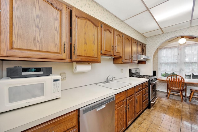 64-66 82nd Pl, Middle Village, NY 11379 - kitchen featuring stainless steel appliances, under cabinet range hood, light countertops, arched walkways, and wallpapered walls