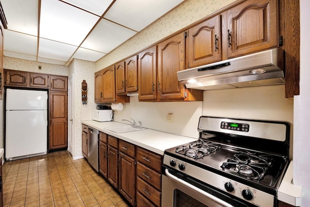 64-66 82nd Pl, Middle Village, NY 11379 - kitchen with stainless steel appliances, under cabinet range hood, wallpapered walls, light countertops, and brown cabinets