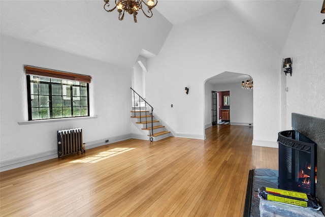 1 Highwood Way, Larchmont, NY 10538 - unfurnished living room featuring radiator heating unit, a chandelier, arched walkways, hardwood / wood-style floors, and stairs